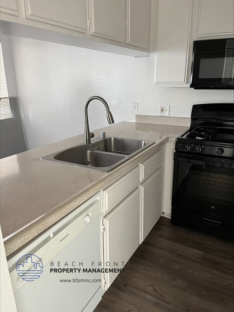 an empty kitchen with white cabinets and a sink